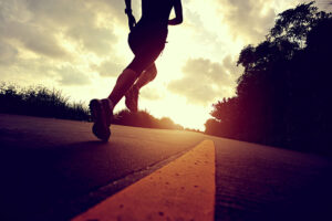 mulher que faz parte de uma assessoria esportiva correndo no asfalto